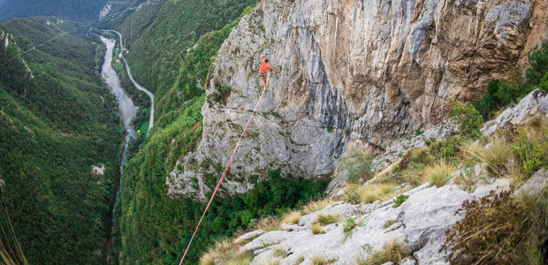 一个人正沿着一条拉长的吊索行走山中的高线人抓住平衡走钢丝者在大自然中的表现Highliner以山脉背景图片