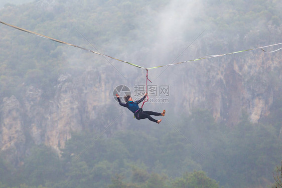 女孩跌倒在拉伸的吊索上山中的高线女人失去了平衡走钢丝者在大自然中的表现Highliner挂在绳子上图片