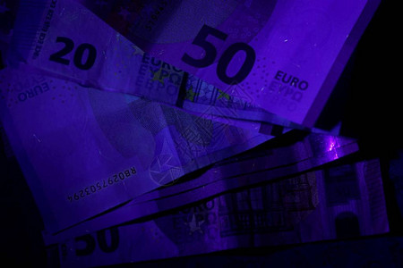 紫外闪光灯束中的钞票背景图片