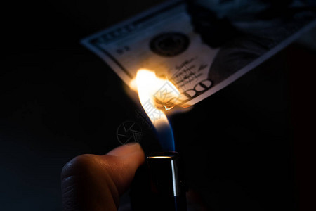 燃烧的美元和手中的打火机特写图片