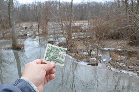 手持一美元钞票或在湿地带冷冻水图片