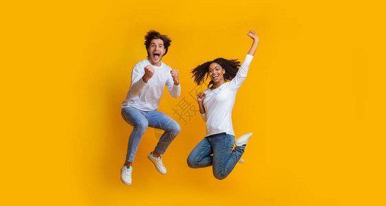 喜悦的多种族夫妇在空中跳跃和庆祝成功图片