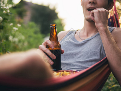 年轻人在户外休息的吊床和喝啤酒图片