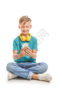白色背景上带耳机和手机的小男孩图片