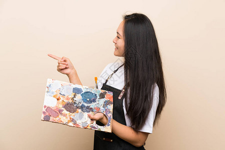 青少年画家和年轻女孩指着一面图片