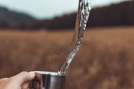 风景背上带金属杯溅水的男人手户外概念背景图片