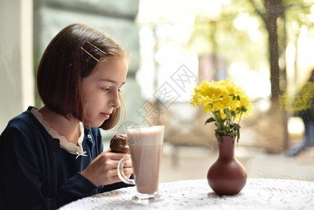 小女孩在咖啡馆里喝热巧克力女学生在咖啡馆里喝可女孩在咖啡馆下课后喝可背景图片