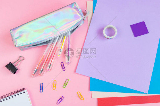 粉红色背景上带有笔回形针书签多色纸和其他文具的铅笔盒图片