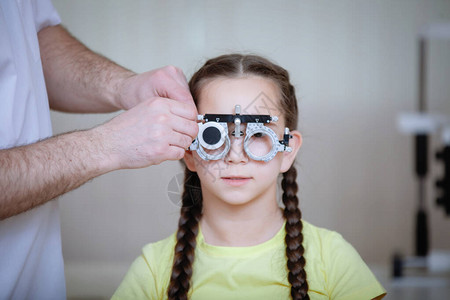 眼部检查由Ophthalmalogist测试眼镜框为身穿黄色短袖圆领汗背景图片