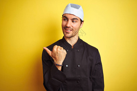 年轻英俊的厨师在孤立的黄色背景下做饭时身着制服和帽子图片