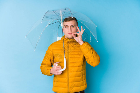年轻的caucasian男子拿着一把伞用手指着嘴图片