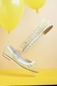 一对黄色夏季皮革女鞋在黄色的气球上飞背景图片