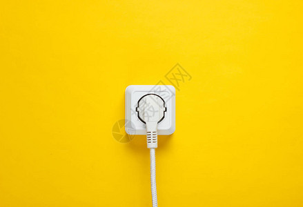 白色电缆插在黄色墙壁背景图片