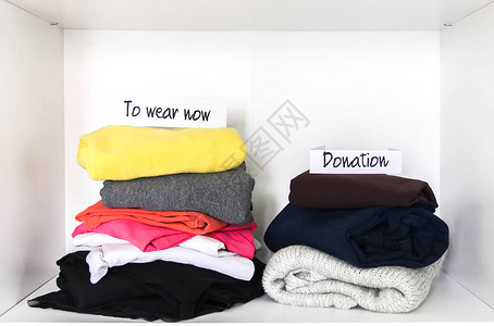 穿戴和捐赠衣物在衣柜中分类白色架子背景上的不背景图片