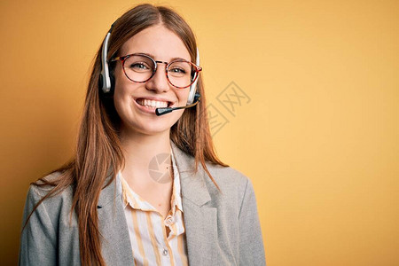 红发年轻人呼叫中心探员穿戴眼镜工作过度的女人戴着耳机图片