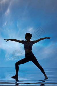 蓝色背景下做瑜伽的女性剪影图片