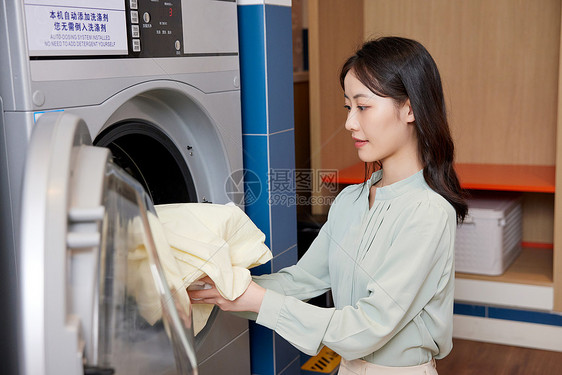 用洗衣机洗衣服的职场女性图片