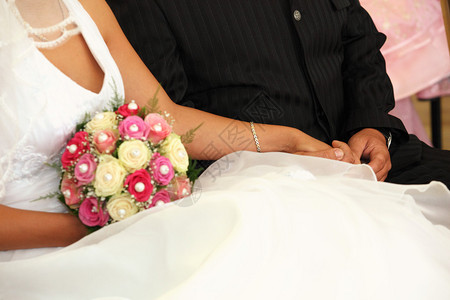 夫妻在她手里拿着新娘的布包坐着图片