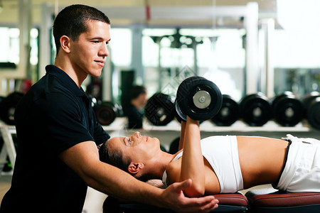 健身房的健身教练用哑铃锻炼图片