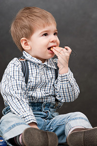 婴儿男孩坐下来吃饼干图片