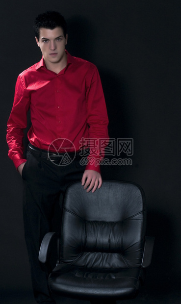 身穿红衬衫的商人在空椅子后面挥着黑衣图片