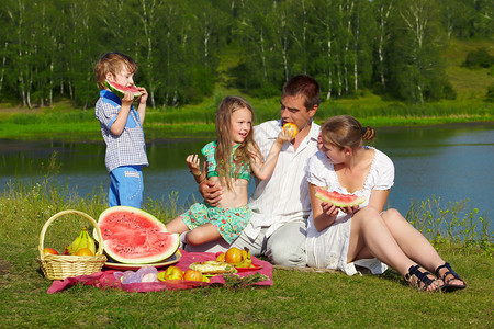 欢乐家庭在公园绿草地野餐享受水果的图片