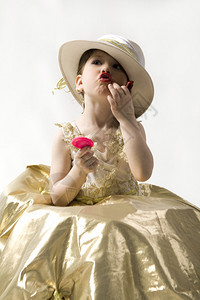 穿浅金色礼服白帽子的黑褐发小甜美女孩编背景图片