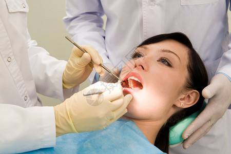 女病人在由助理辅助检查其牙齿时张开嘴检查其牙图片