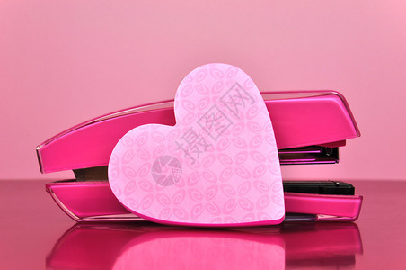 漂亮的粉红色办公配件订书机和粉红色的心形便笺纸图片