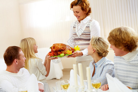 大家族的肖像坐在节庆桌边看着吃美味火鸡盘背景图片