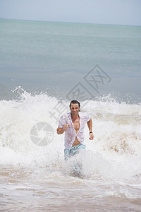 健康的年轻人穿着白衬衫微笑地跑出大海图片
