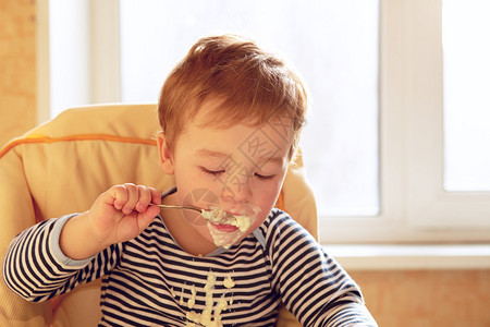 早上吃粥的两岁男孩的肖像背景图片