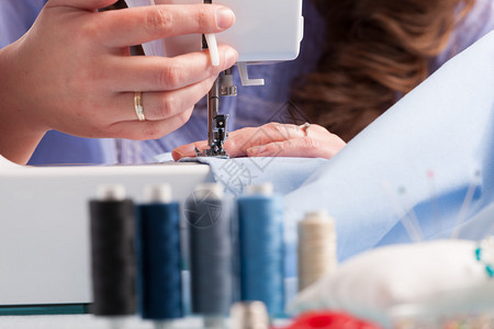 妇女手用缝纫机彩色线条和诸如针纽扣和脚印等其他缝纫图片