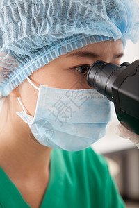 一个女人通过显微镜观察分子的垂直图像图片