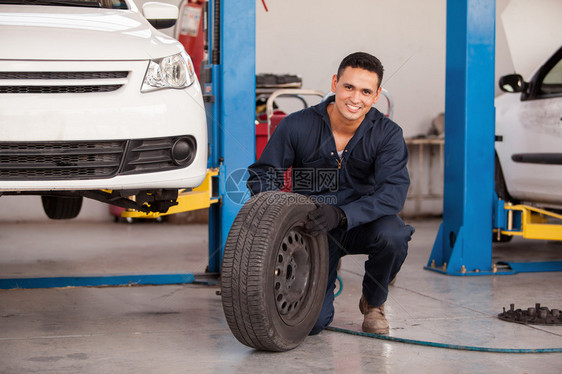 在汽车修理厂修理轮子的男技工图片
