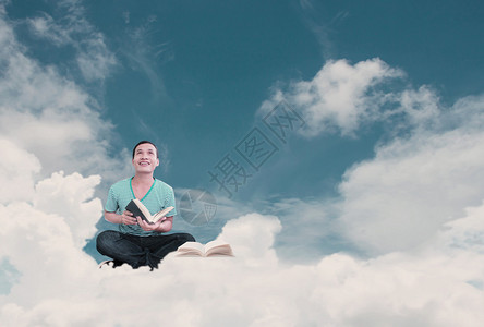 年轻男人在云中读书梦想的概念图片