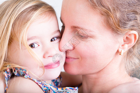 美丽的年轻慈爱的母亲吻她的漂亮女儿图片