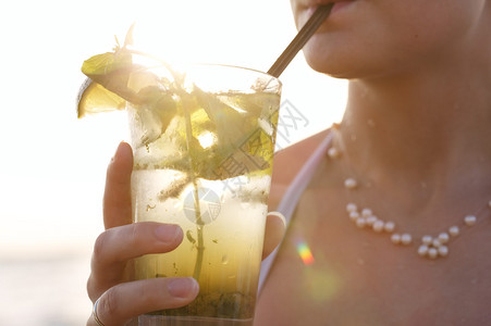 一位近距离享受热带莫吉托鸡尾酒的女人日落时分在海边盛满鲜果子通图片