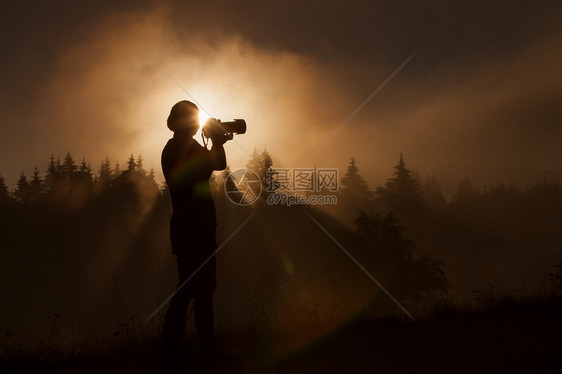 女摄影师在有雾的森林里拍照的剪影图片