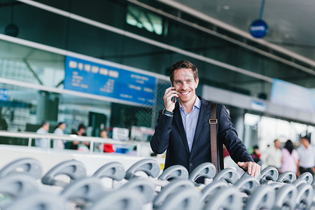 机场推车商人在机场一排行李推车旁边用电话聊天时使用电话交谈背景
