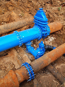 欧美接头旧的大饮用水管与新的蓝色阀门和新的蓝色接头成员相连完成修复管道等待粘土覆盖极端的那种腐蚀背景