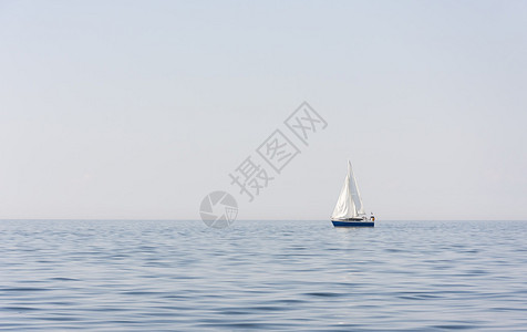 在海上或海上有白帆的蓝色帆船图片