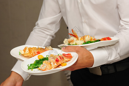 服务员手拿着准备好的龙虾和海草的盘子图片