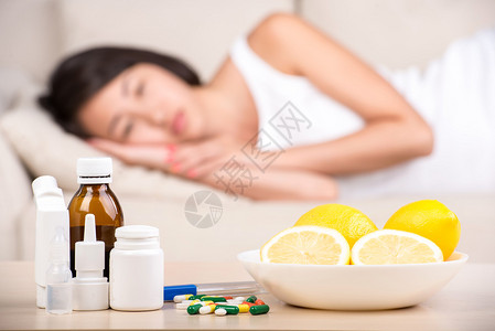 桌子上有药品和柠檬背景是床上的阿西亚女图片