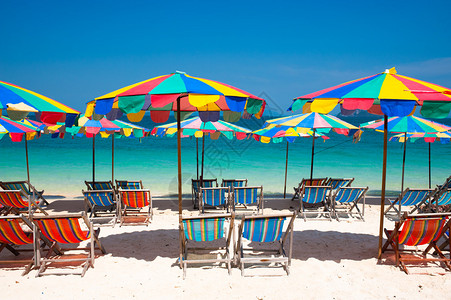 在泰国普吉岛海滩五颜六色的伞下的露营床图片