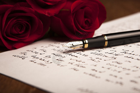 钢笔纸和鲜花玫瑰的静物特写图片