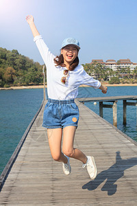 年轻美女在滨海的木码头跳上欢快的情绪跳跃的肖像图片