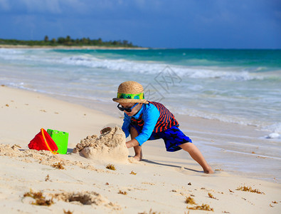 小男孩在夏日海滩上建造沙堡图片