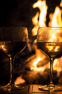 两杯葡萄酒由营火旁的两杯红酒在这张闪亮背景图片