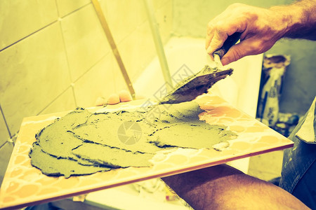 建筑泥工手与瓷砖一起工作的老式照片图片